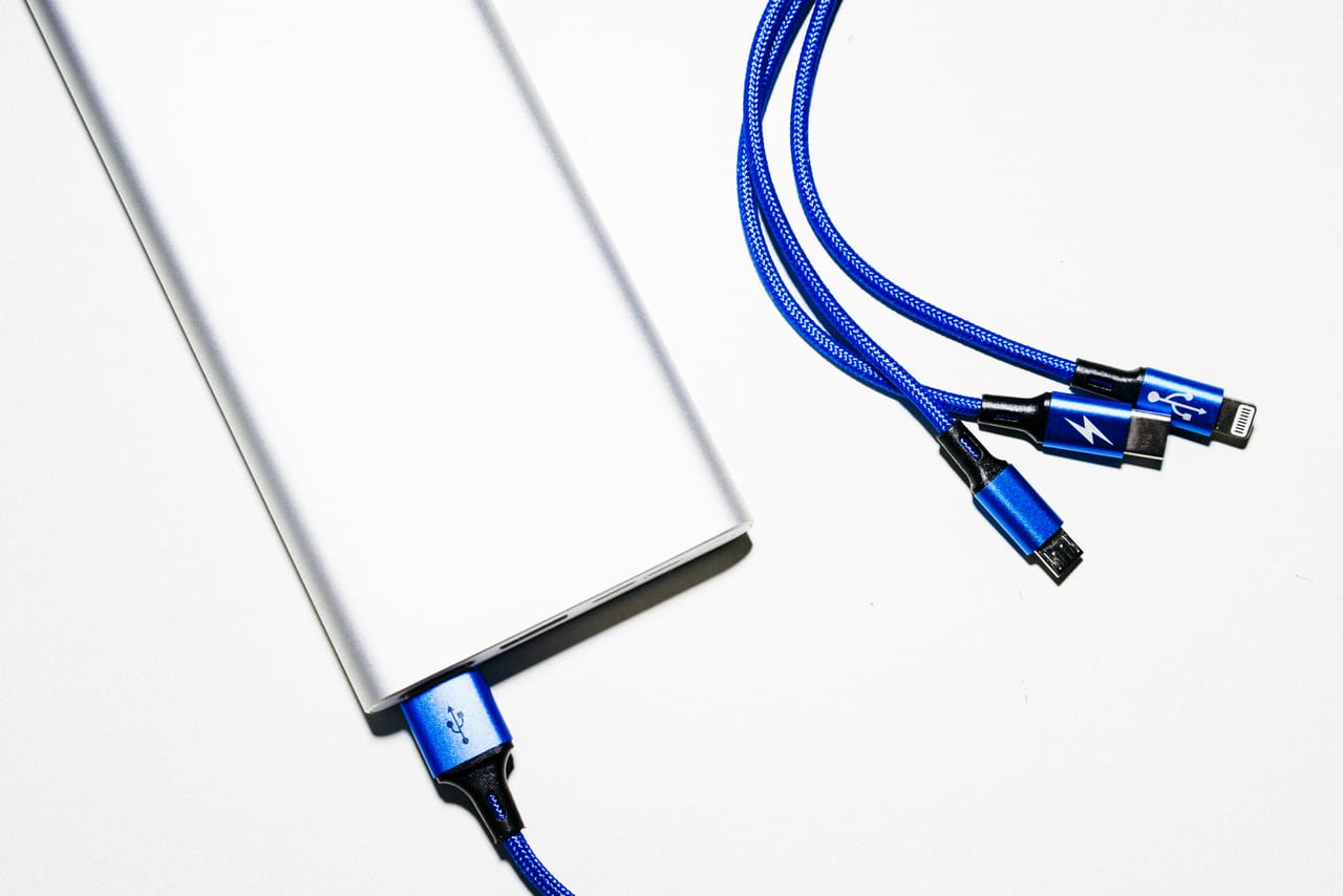 A power bank, loose lithium batteries and an aerosol can on a plain surface