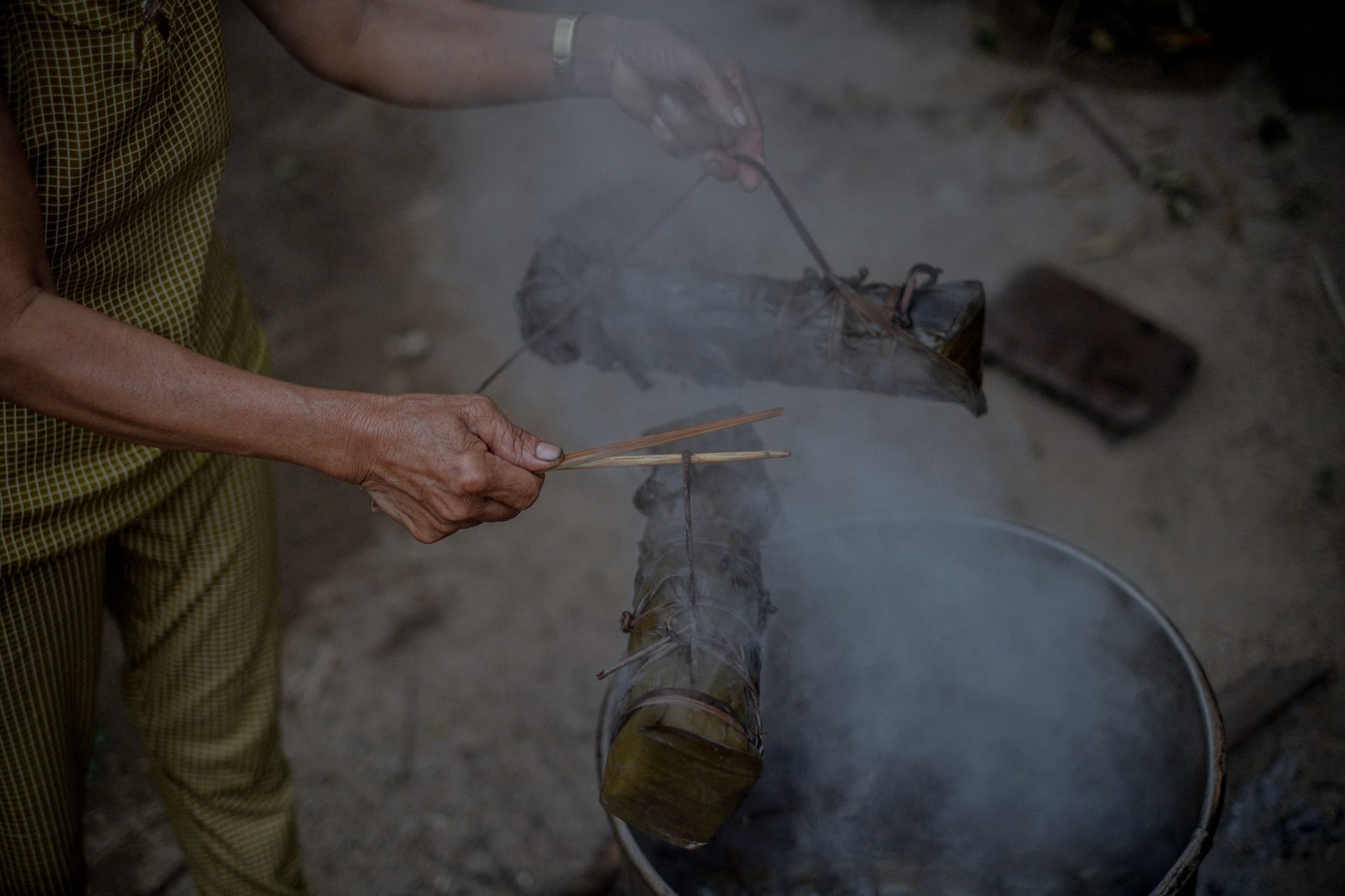 A cook slowly turning ribbons of beef over smoking embers to make se'i sapi on Rote island