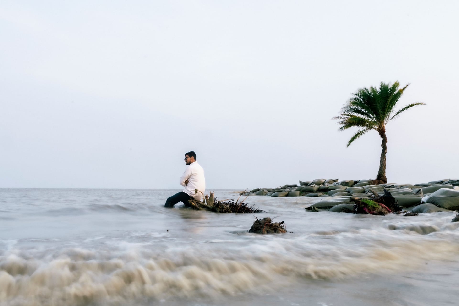 Remote worker on a laptop at a beachfront warung on Rote island at dawn with a Starlink dish nearby