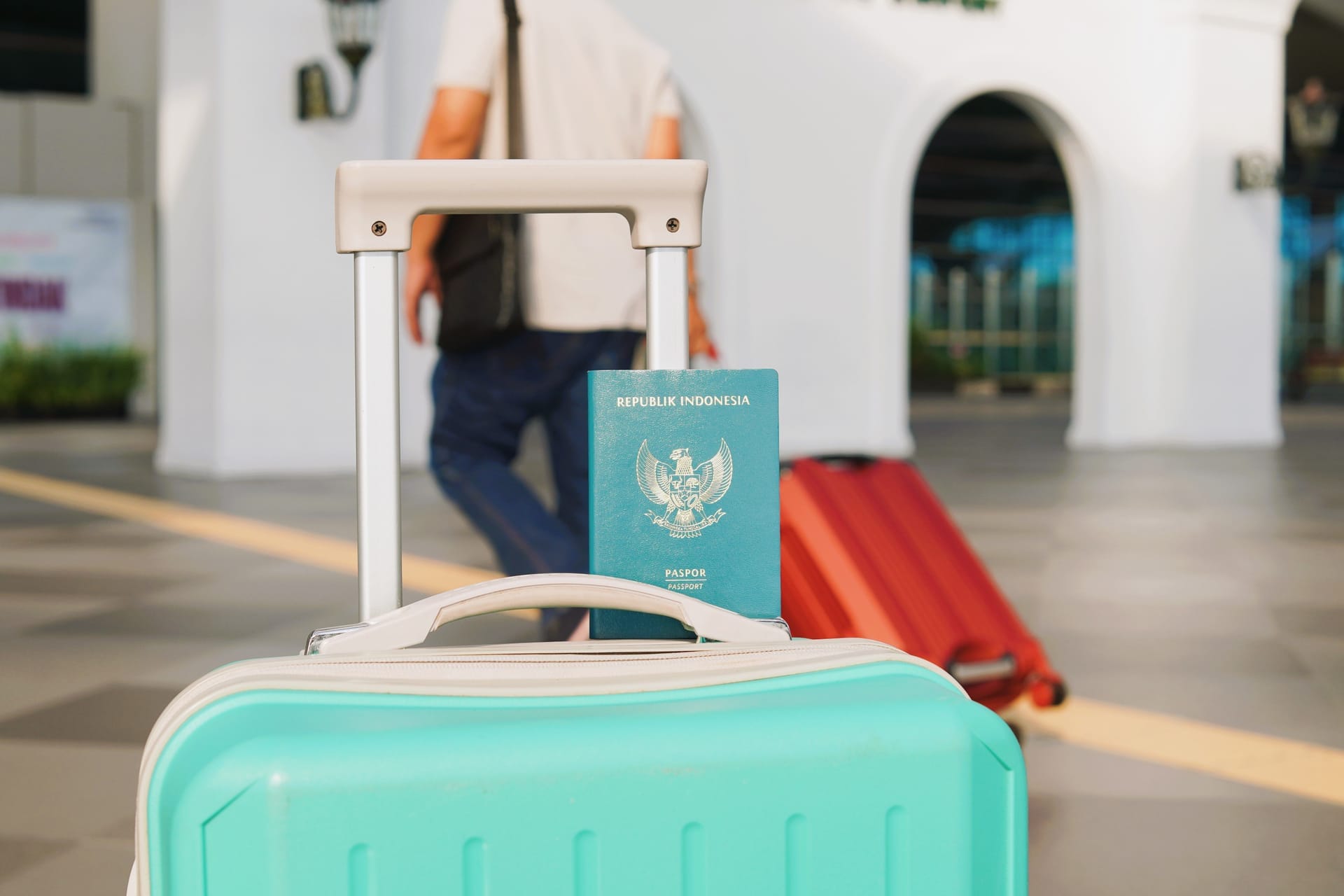 Traveler holding a passport and boarding pass at a small Indonesian island airport in warm morning light