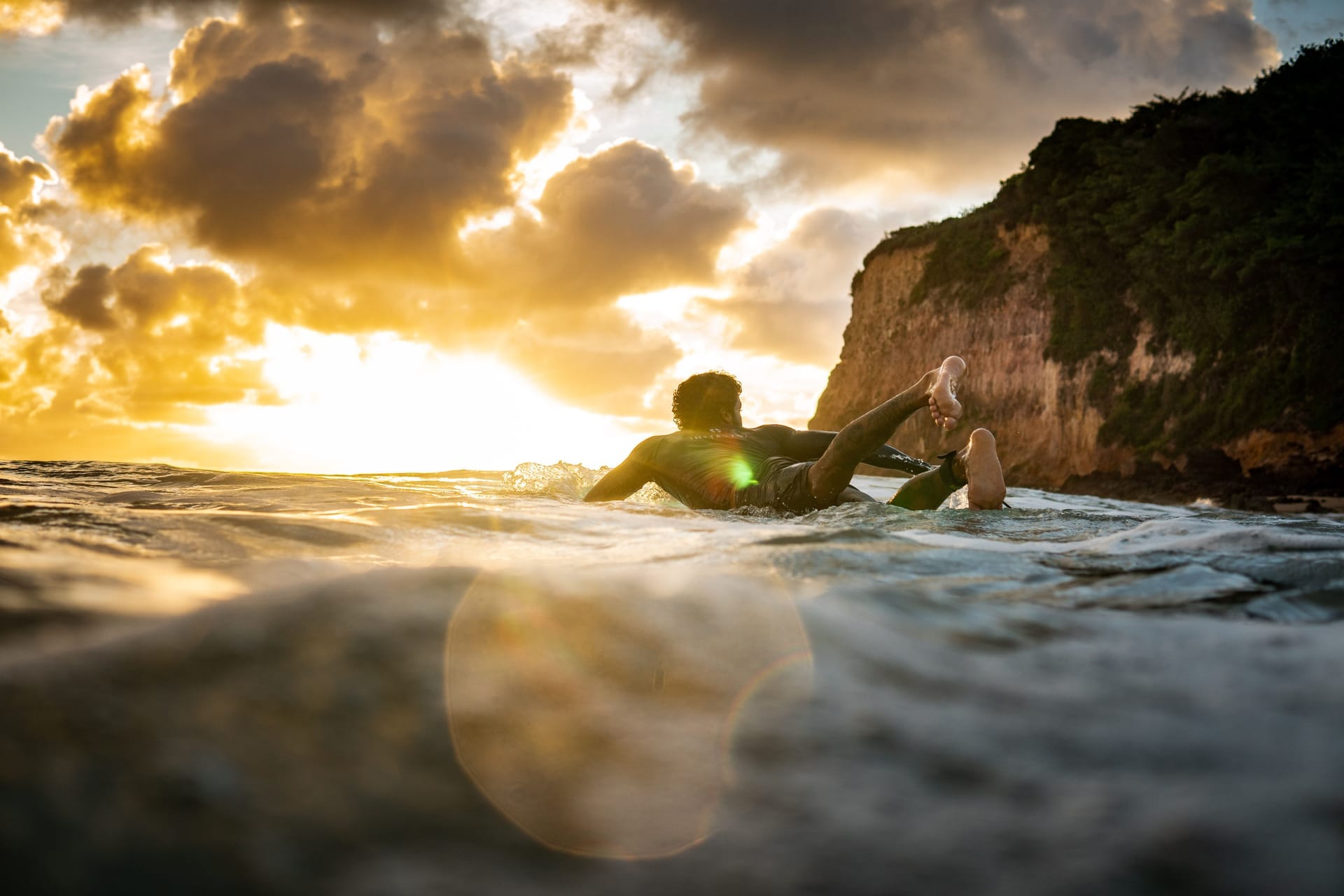 A solitary surfer paddling out to an empty reef break off Rote at dawn under offshore morning light