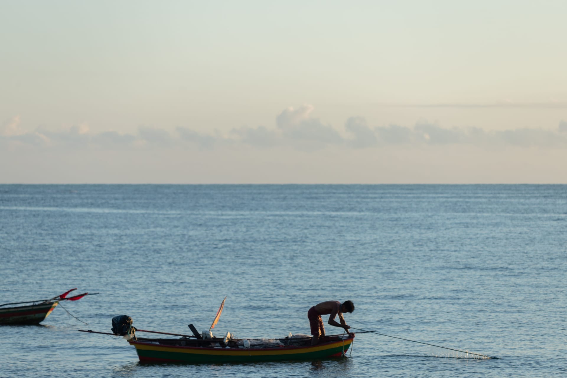 A remote worker at a laptop on a seafront veranda on Rote, with a Starlink dish beside them and the ocean behind