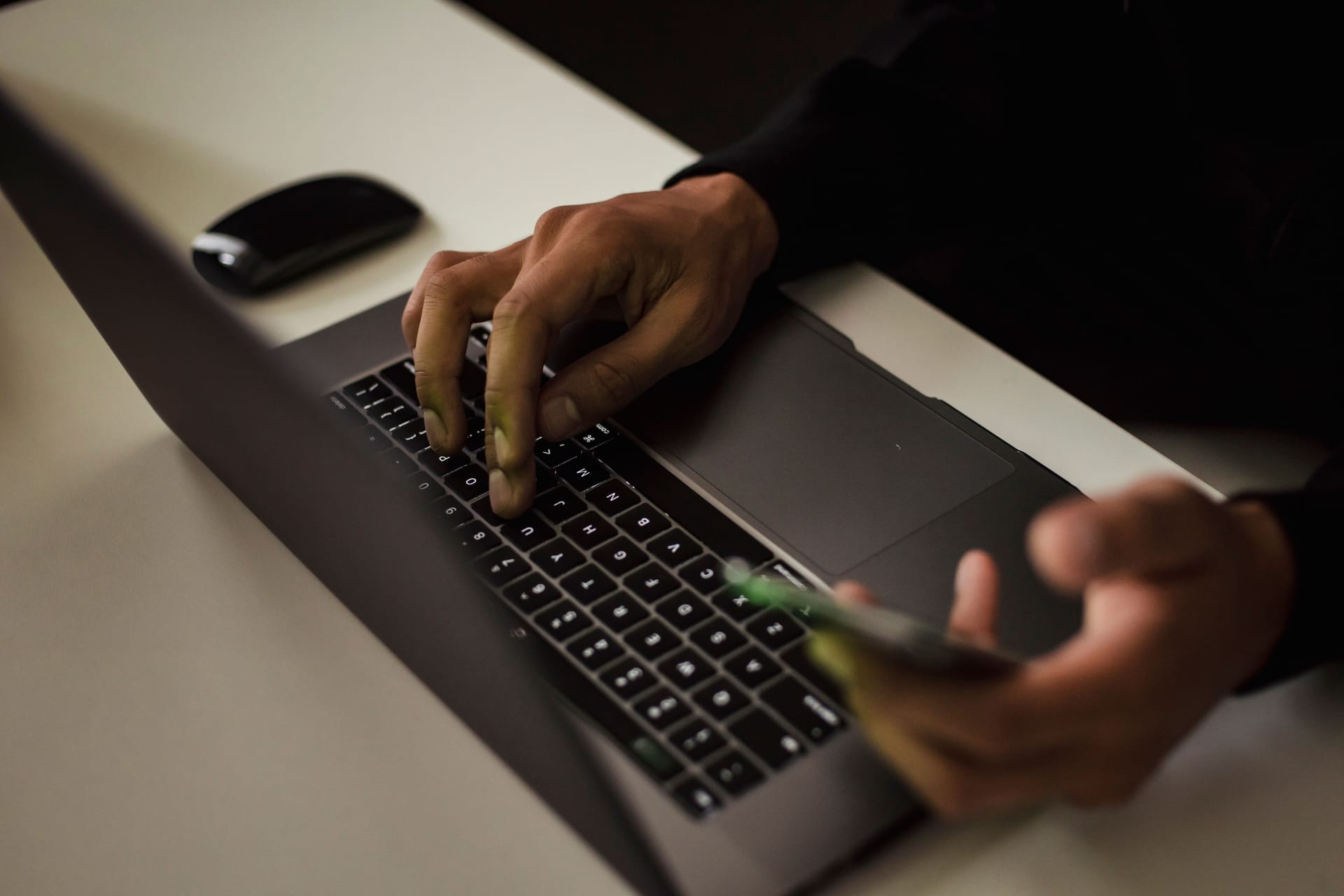 Remote worker on Rote island holding a phone beside a laptop as the power fails in a simple home workspace