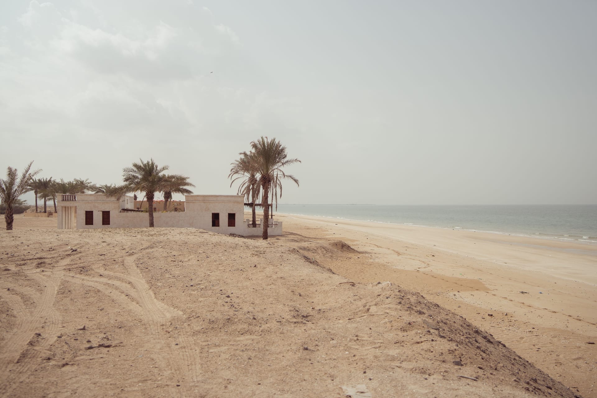 An empty shuttered beachfront house on Rote island at dawn with palms and turquoise ocean behind it