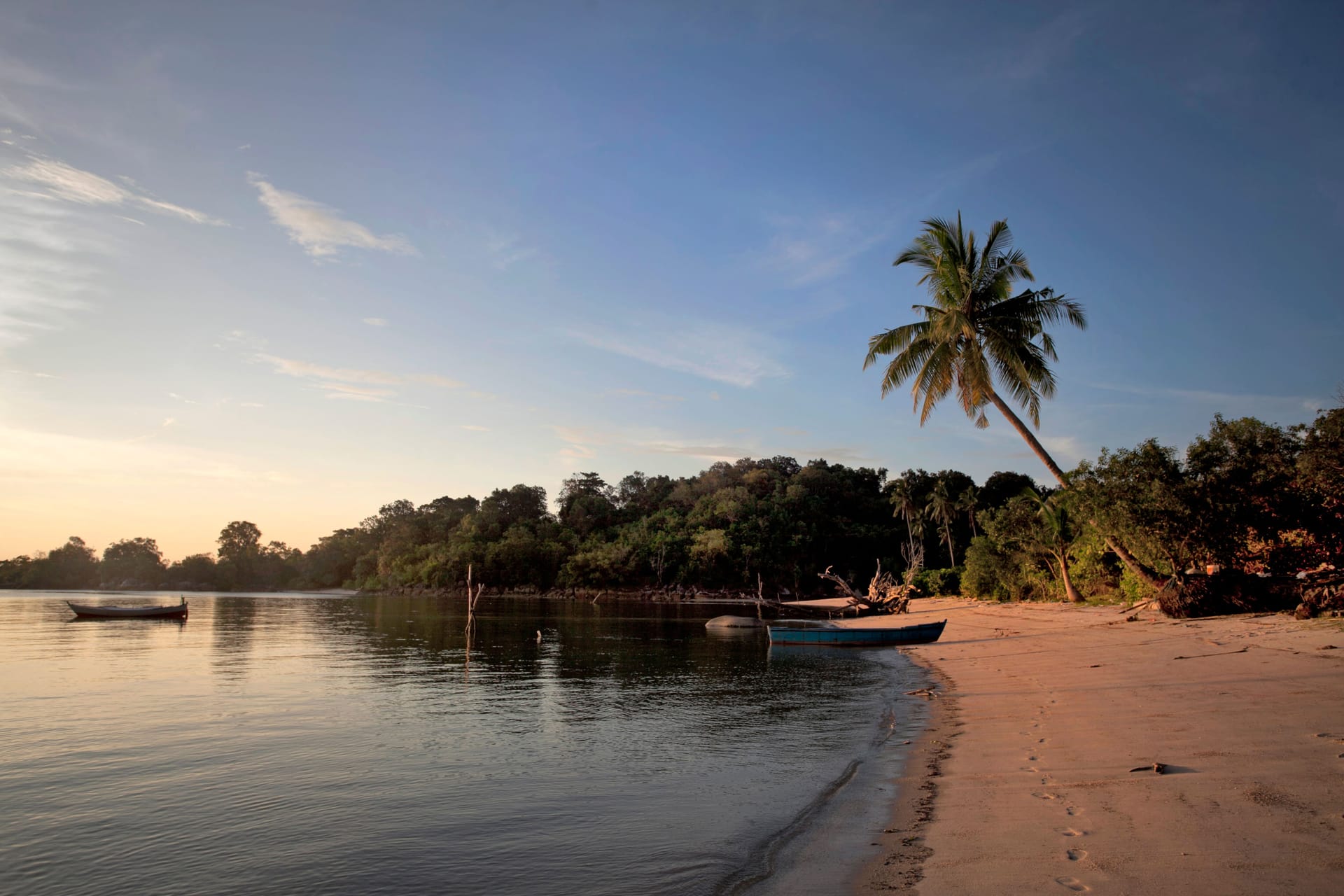 Glassy flat sea at dawn in front of Nemberala village on Rote, with fishing boats resting on still water over the reef