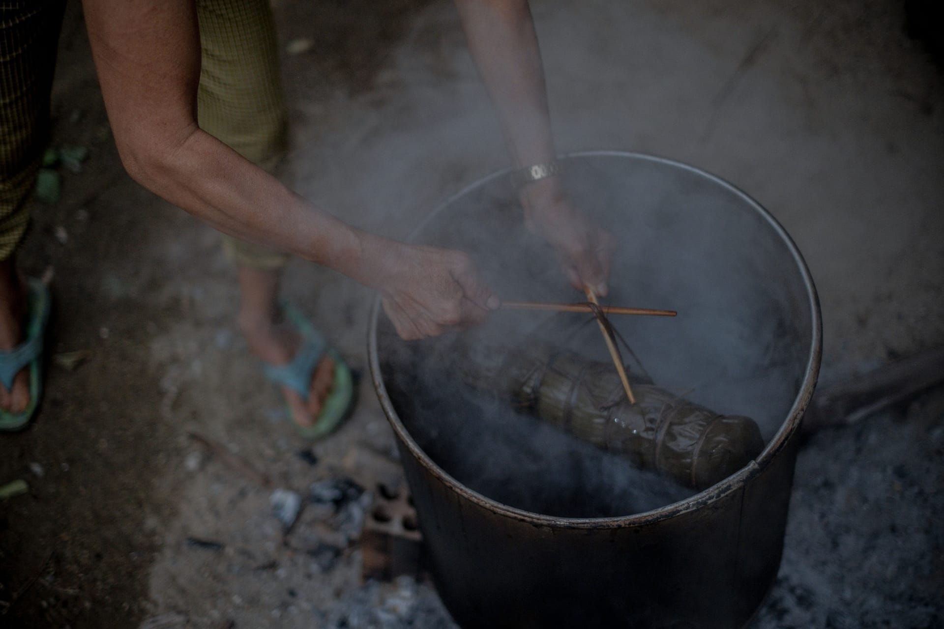 A local pit smoker slowly smoking thin strips of se'i sapi beef over a wood fire in warm morning light