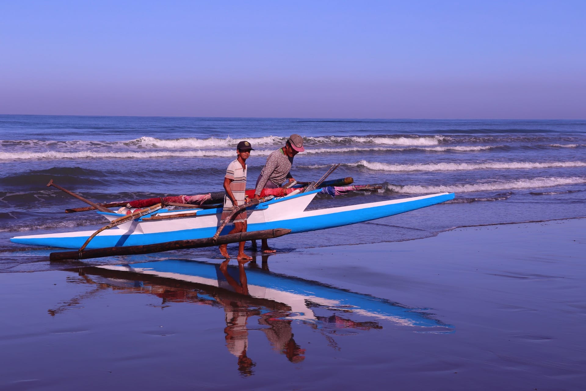 Workers loading cargo and a motorbike onto the Kupang to Rote ferry in early morning light