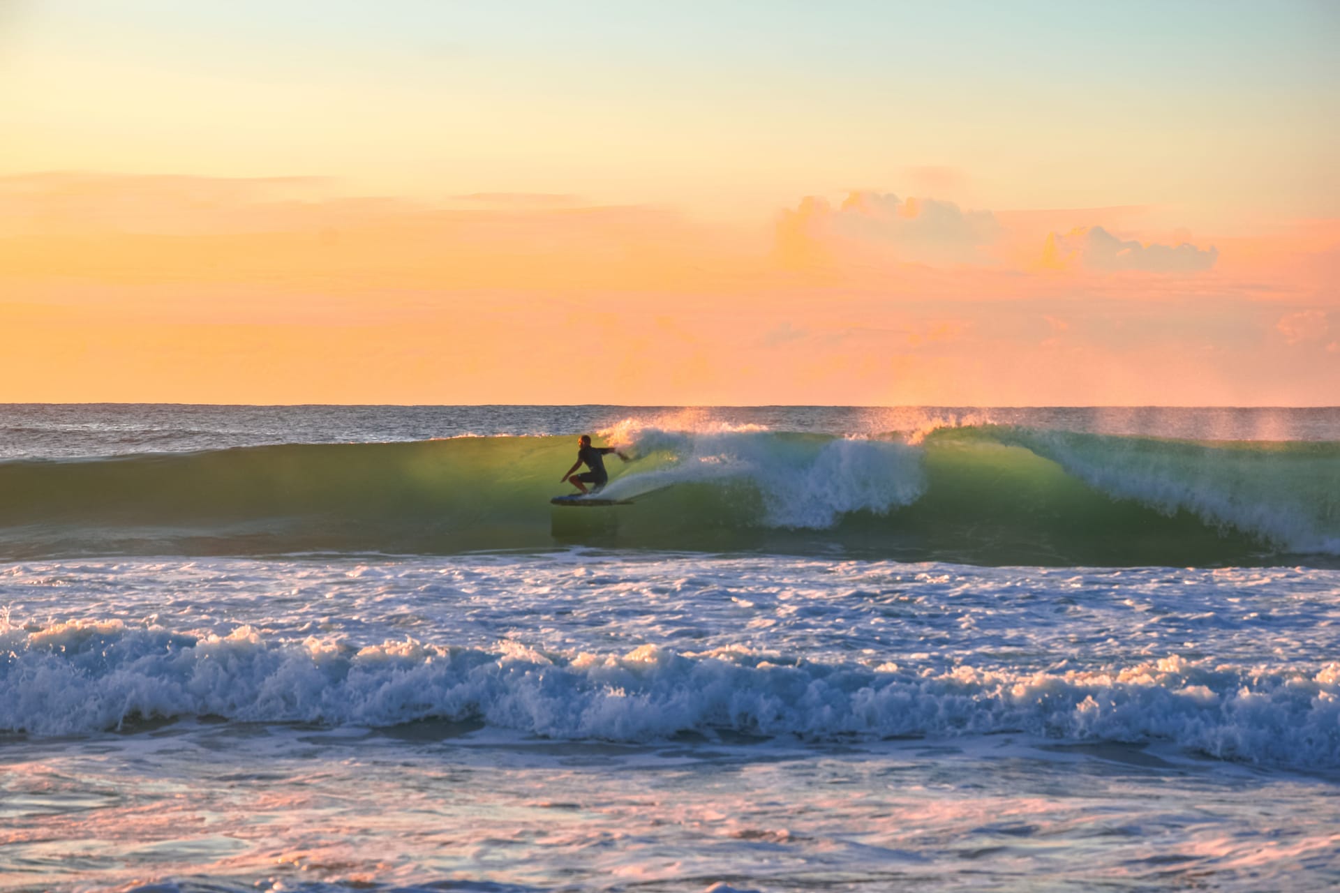 A lone surfer paddling out to an empty reef at dawn near Nemberala, Rote