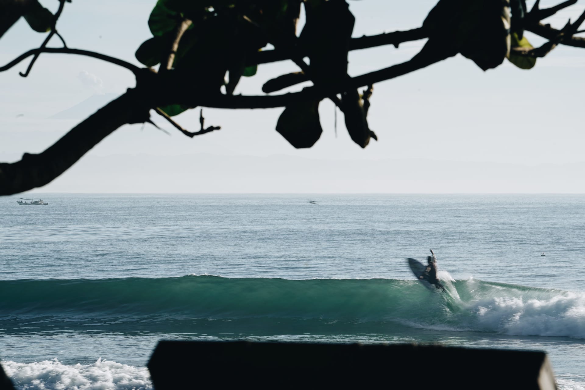 A surfer repairing a surfboard ding by hand on an island deck at dawn, with no surf shop nearby