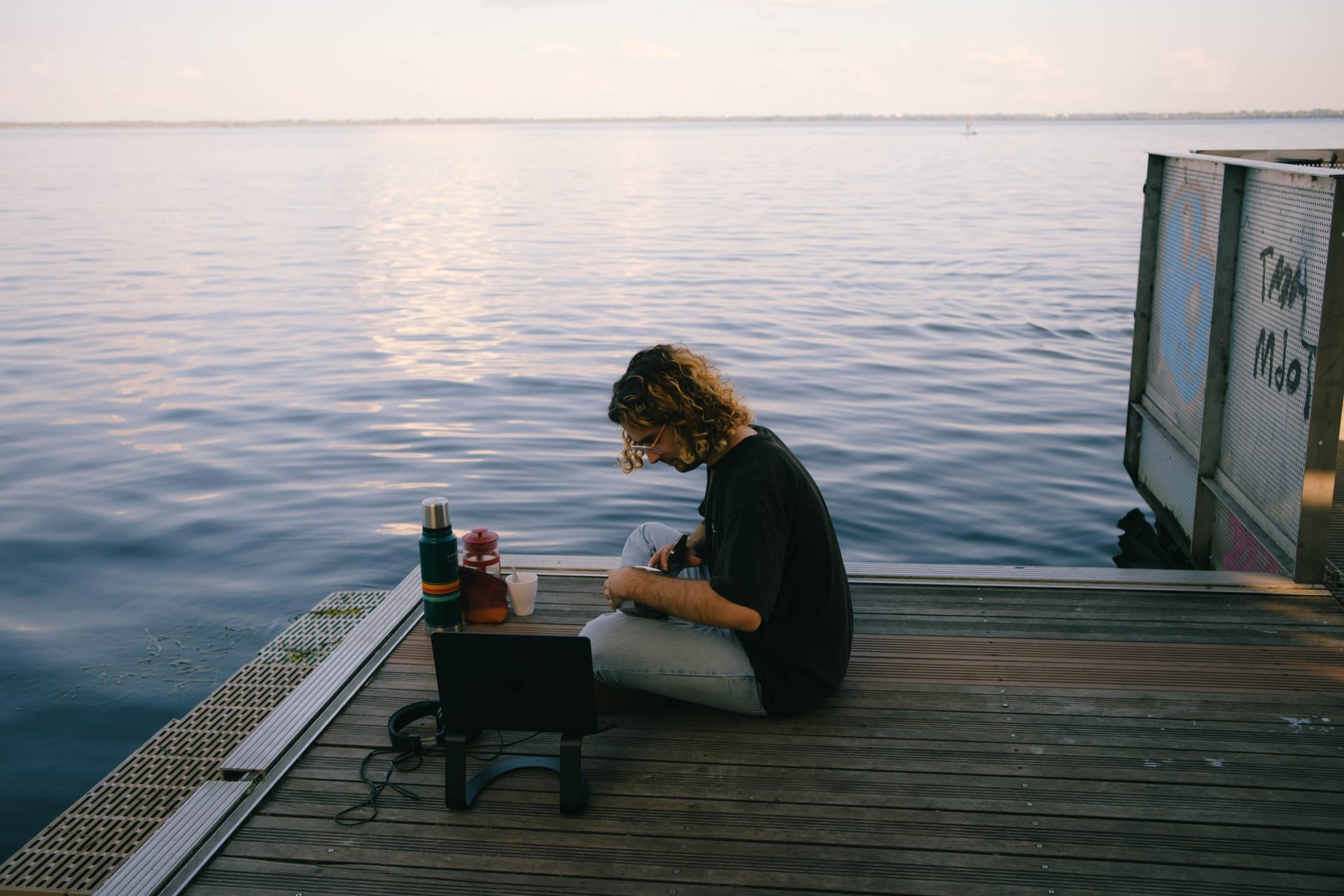 Remote worker with a laptop on the porch of a bamboo beachfront bungalow on Rote island at sunrise