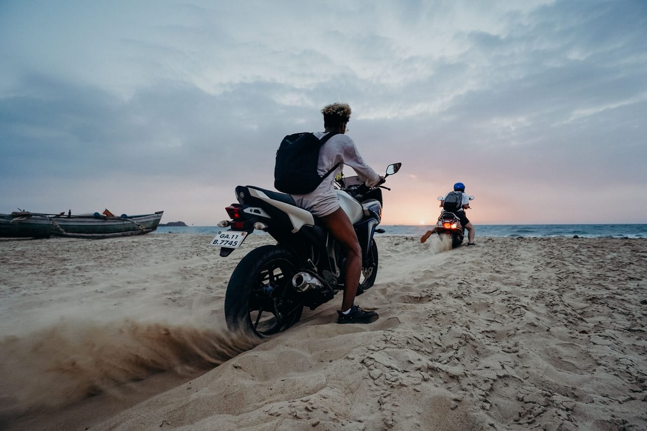 Foreign resident riding a motorbike on a dirt road past local homes on Rote island