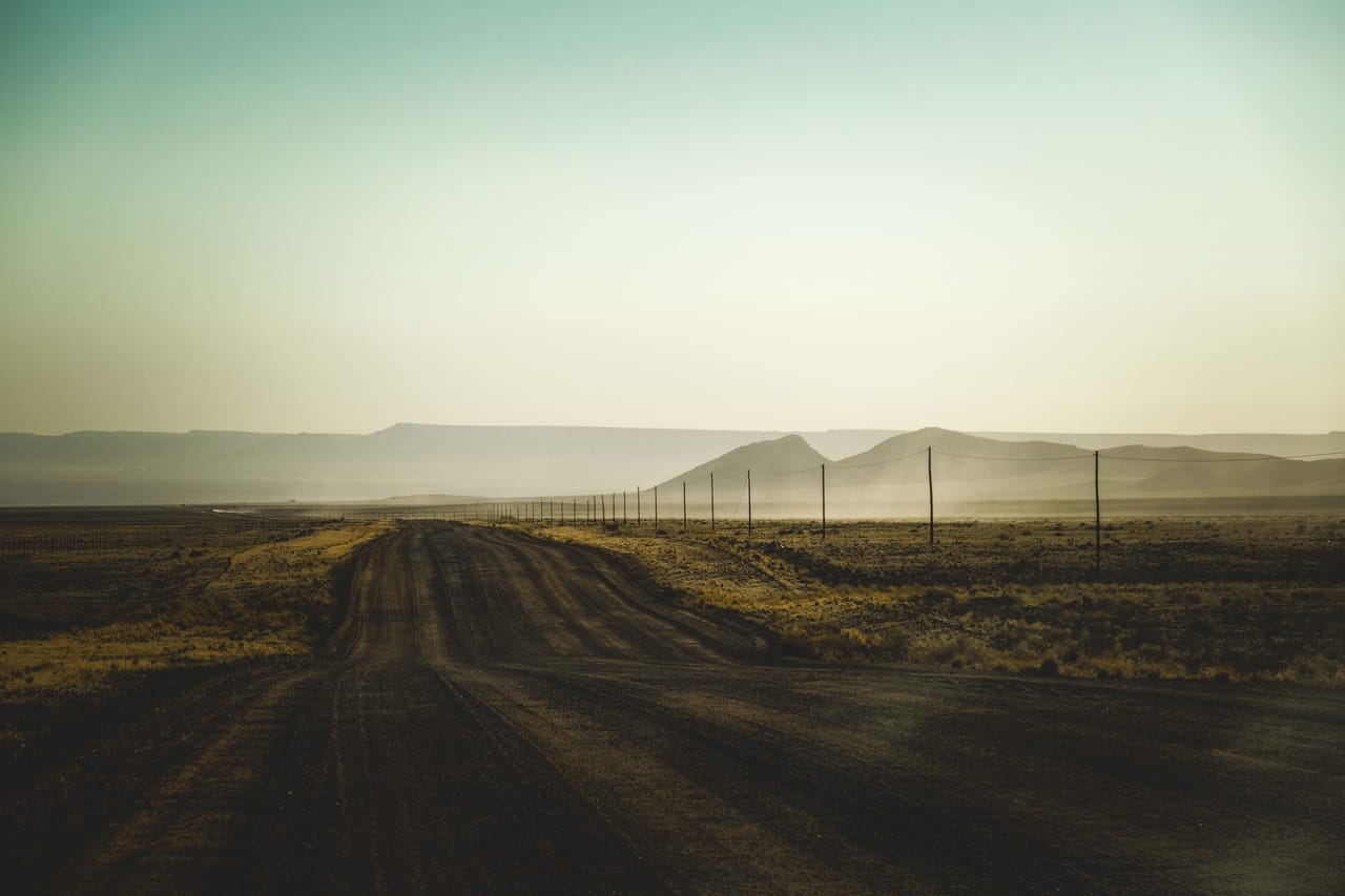 A dry, dusty dirt road cutting through sun-bleached scrub on Rote during the peak dry season