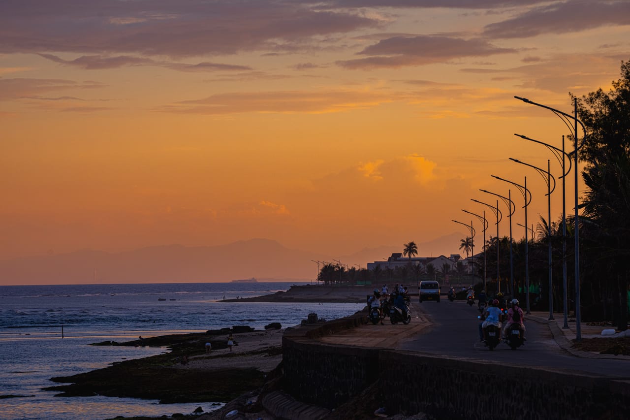 Motorbike rider on a dirt coastal road in Rote at golden hour with the ocean in the background