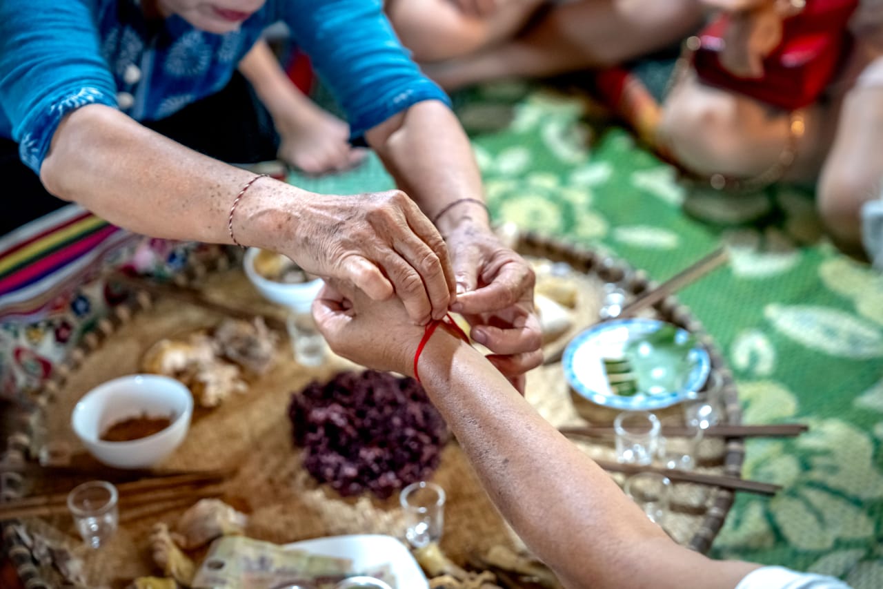 Rotenese family sharing food and sopi palm liquor on a mat during a community gathering