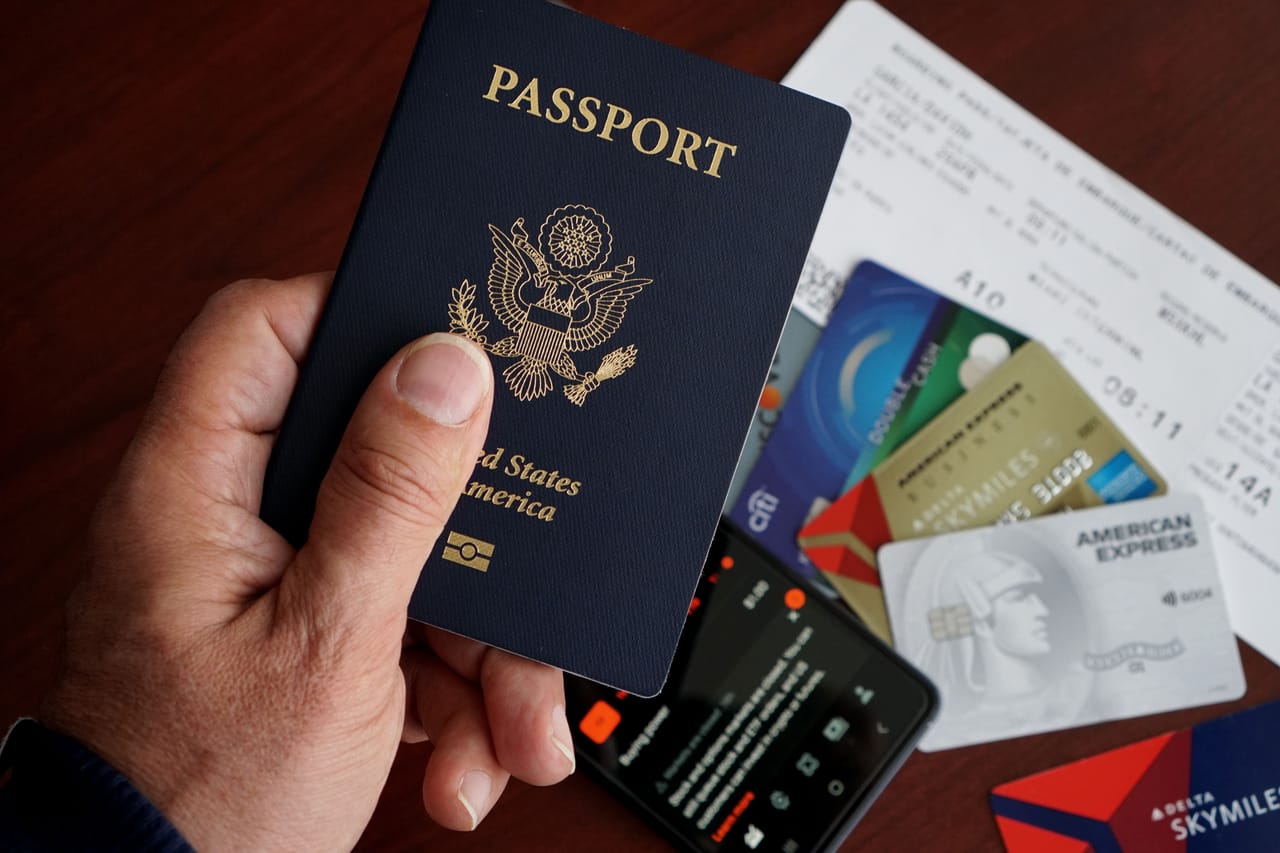 Hands holding an Indonesian KITAS stay-permit card and passport on a wooden table