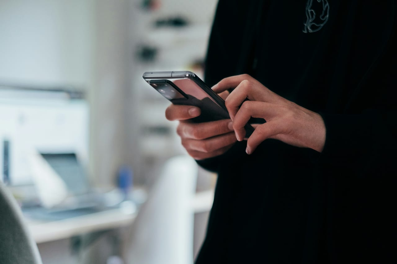 A hand holding a smartphone showing a ride-hailing map on a busy street