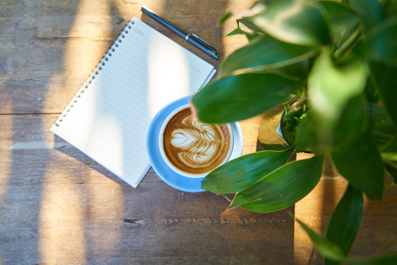 A handwritten Indonesian vocabulary notebook next to coffee at a warung on Rote