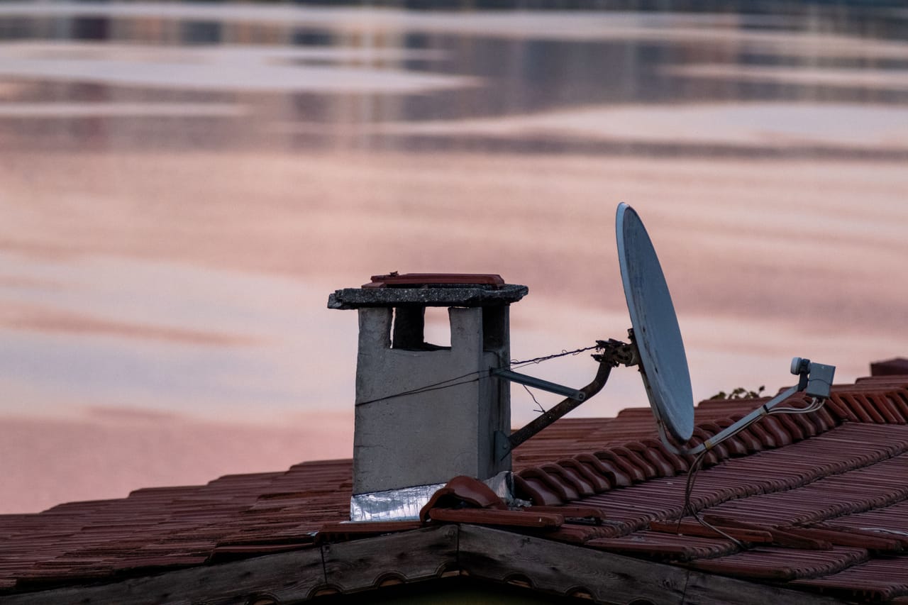 A Starlink satellite dish installed beside a local house on Rote, with a smartphone as mobile-data backup