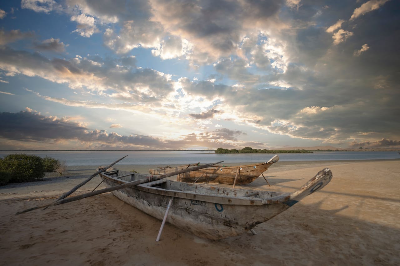 A weathered local fishing boat on the beach at Nemberala with an offshore reef break in the distance