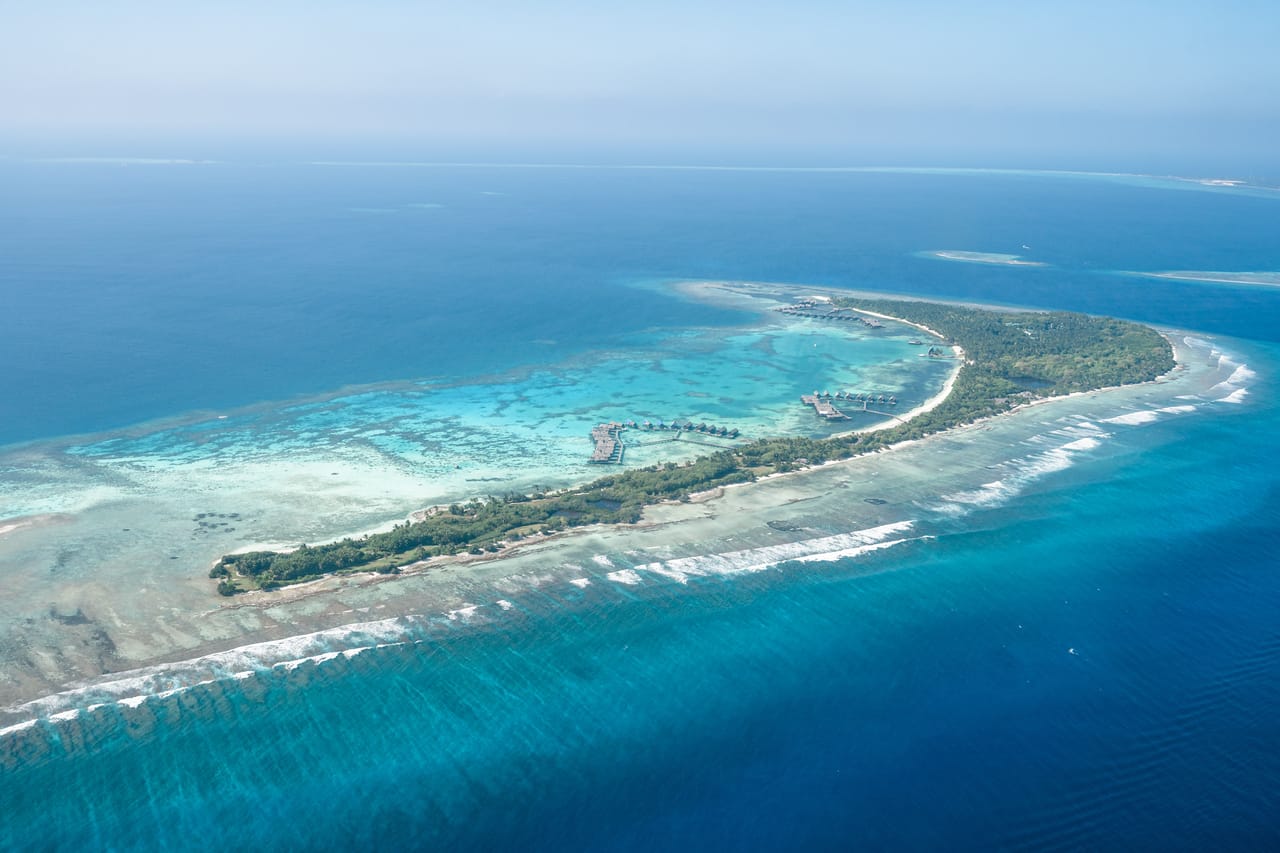 Shallow turquoise reef platform fringing the southwest coast of Rote where the island's surf spots break
