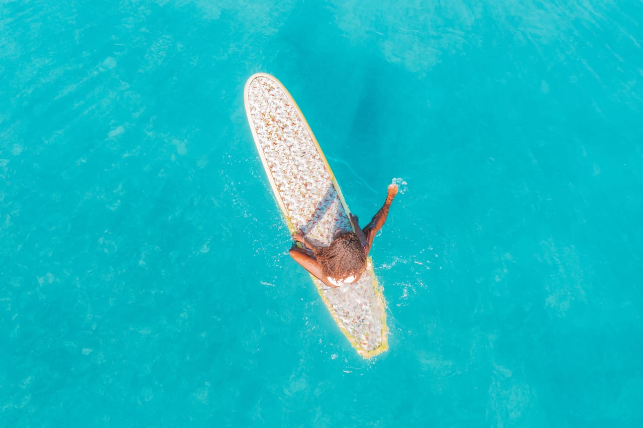 Lone surfer waiting in an empty lineup off Rote as the reef sits flat under afternoon light