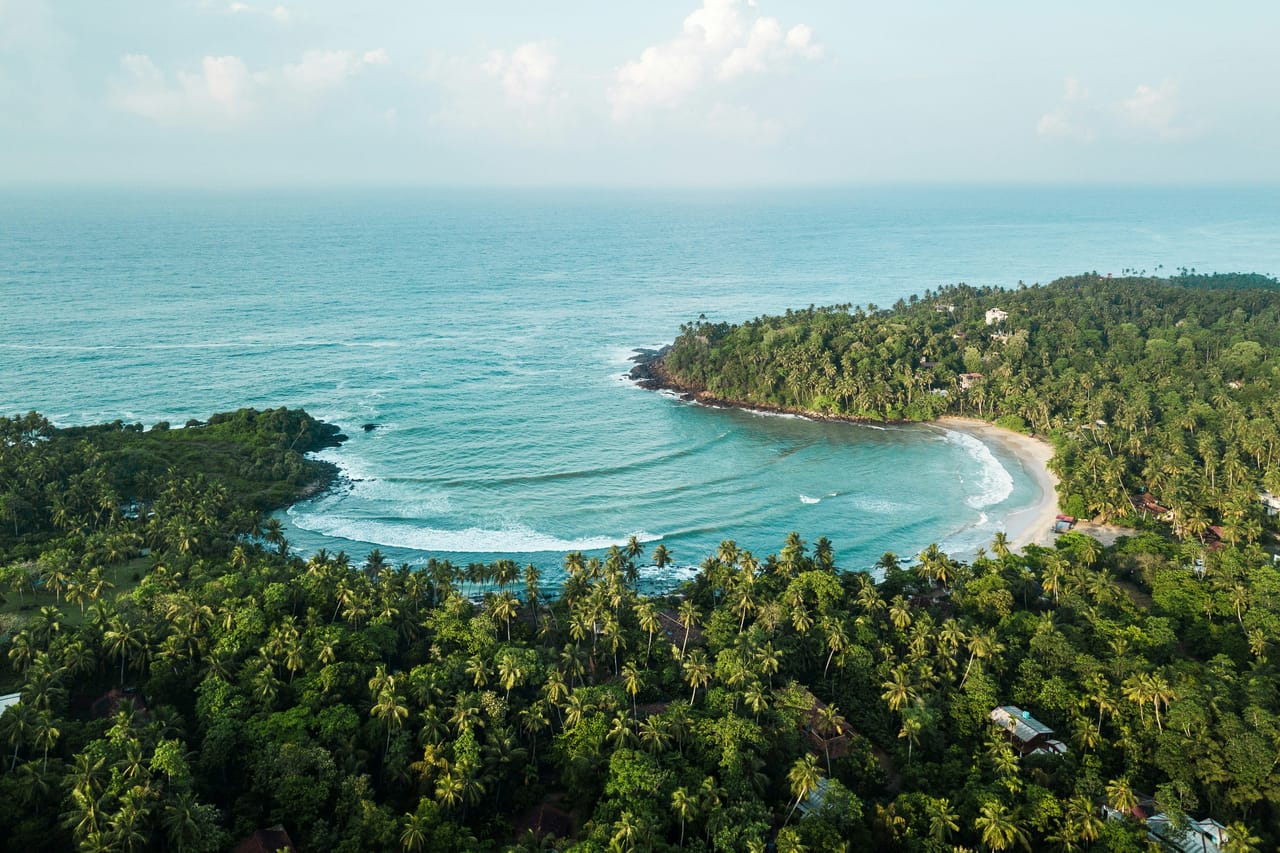 Aerial view of two small islands and a tiny islet set apart in a wide blue sea
