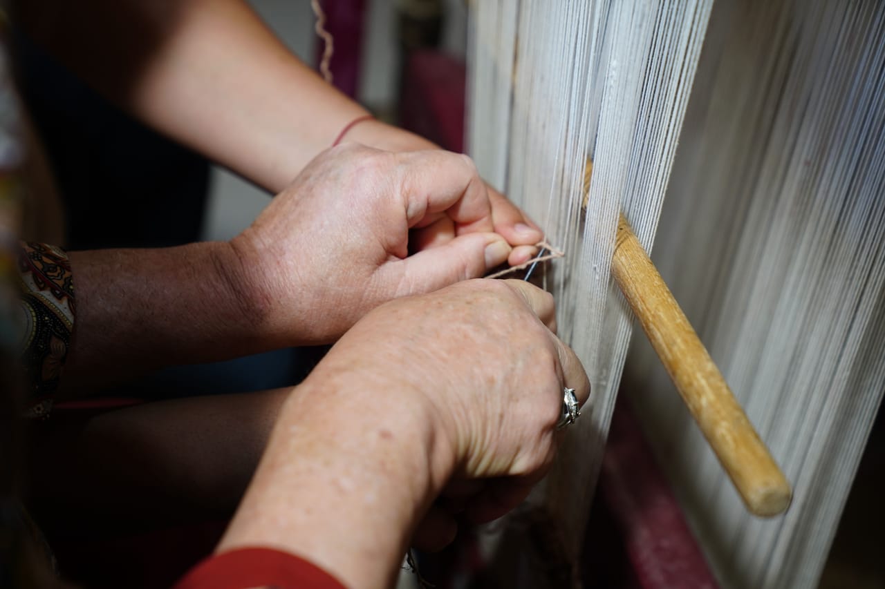 Savunese woman weaving fine ikat cloth with intricate stripe patterns on a traditional loom