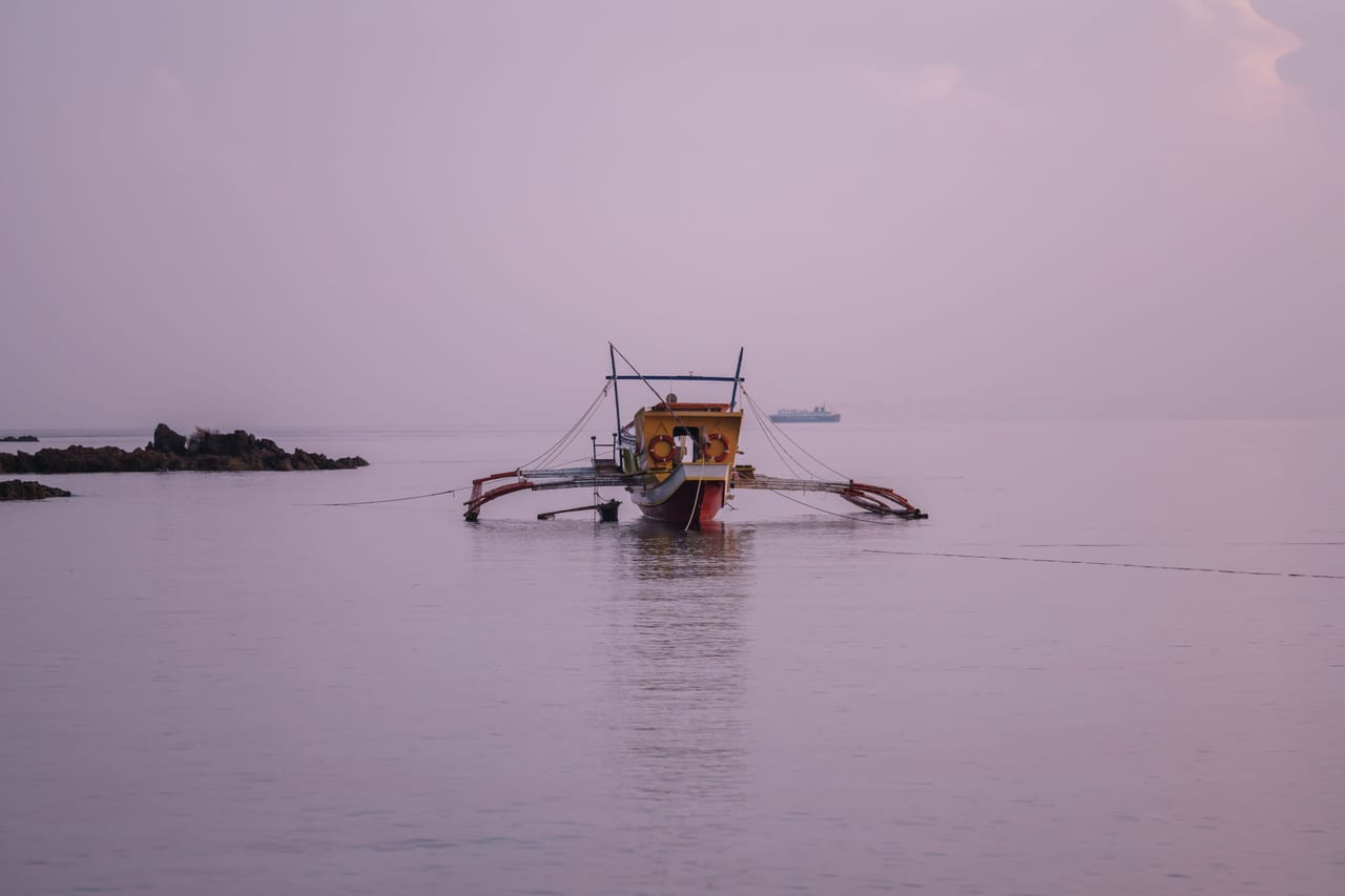 Surfers sharing a boat bench at dawn with stacked boards before a session on Rote