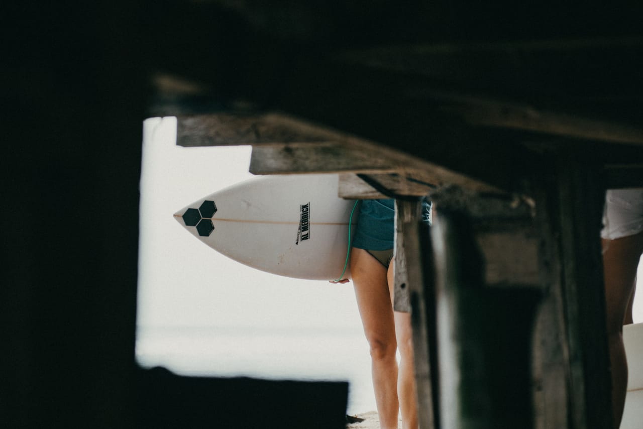 A three-board season quiver of scarred surfboards leaning against a weathered island home wall