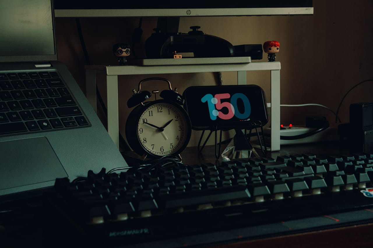 Laptop and phone on a wooden desk showing WITA time next to a European time zone