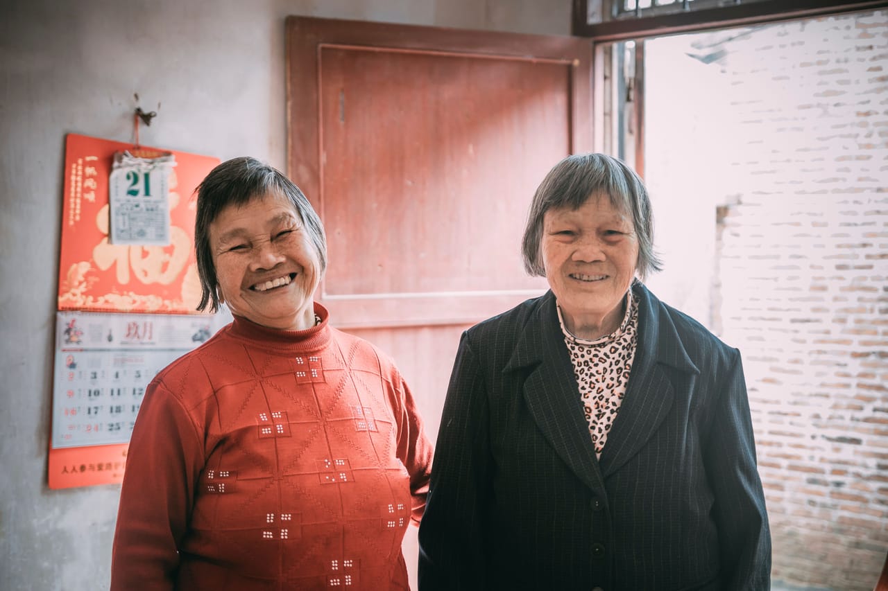 A long-stay retiree talking with a local Rotenese family outside a simple home on Rote